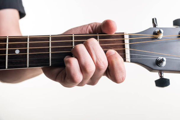 Kitaristin käsi kiinnittää sointu Amin kitaraan valkoisella pohjalla. Vaakakehys
 - Valokuva, kuva