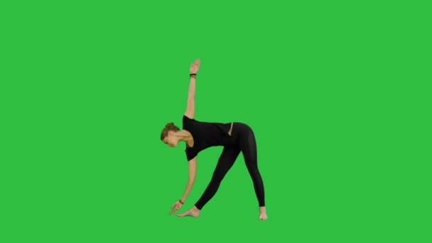 sportlich schöne lächelnde junge Frau steht in utthita trikonasana, ausgedehntes Dreieck posiert auf grünem Bildschirm, Chroma-Schlüssel - Filmmaterial, Video