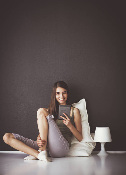 Pretty brunette woman sitting on the floor with a pillow and plane table - Photo, Image
