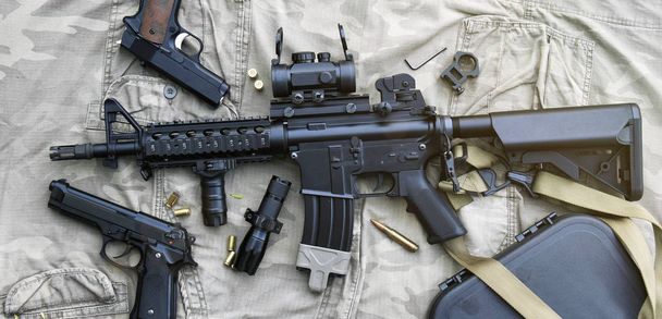 Όπλων και στρατιωτικού εξοπλισμού για στρατό, όπλο Assault τουφέκι (M4a1) και πιστόλι σε φόντο καμουφλάζ. - Φωτογραφία, εικόνα