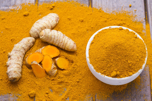Turmeric powder and roots on wooden background - Photo, Image