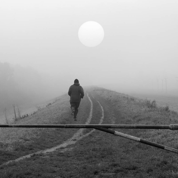 Νεαρός άνδρας τρέξιμο στη φύση σε κρύο ομιχλώδη ημέρα του φθινοπώρου σε μαύρο και άσπρο - Φωτογραφία, εικόνα