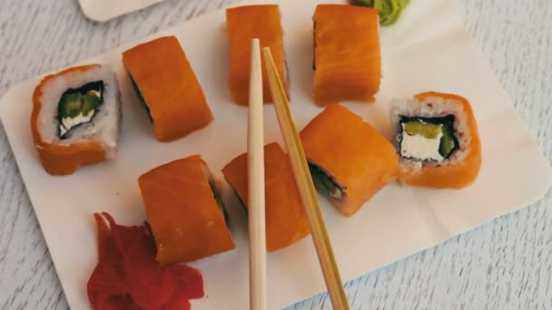 Herkullinen sushi lohen, juuston, wasabin, vaaleanpunaisen inkiväärin, soijakastikkeen kanssa tyylikkäällä valkoisella puupohjalla
 - Materiaali, video