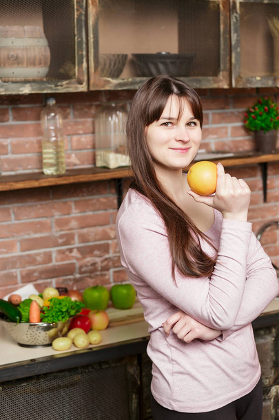 Woman holds an orange in her hand.Young Woman Cooking in the kitchen at home. Healthy Food. Diet. - Фото, зображення