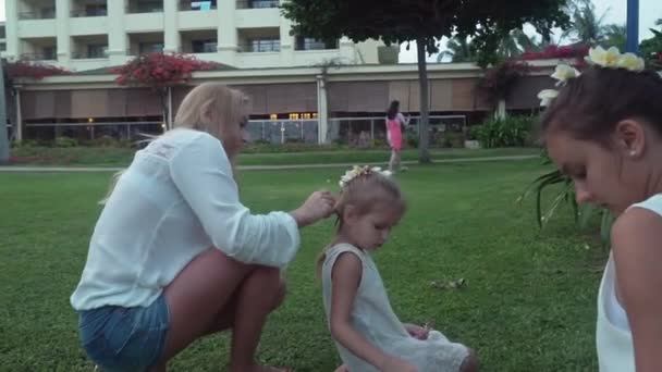 Mom decorates daughters hair with flowers of Plumeria stock footage video - Felvétel, videó
