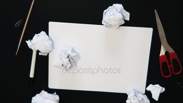 Crumpled paper pieces falls on black table with white sheet - Footage, Video