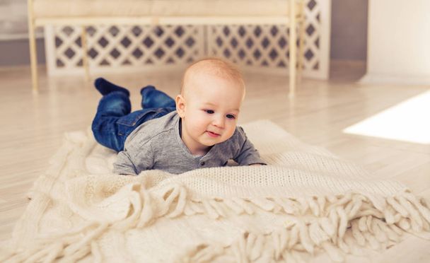 Adorable baby boy in sunny bedroom. Newborn child relaxing. Nursery for young children.Family morning at home. Little kid lying on tummy - Photo, Image
