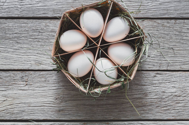 Huevos blancos de pollo frescos en cartón sobre fondo de madera rústica
 - Foto, Imagen