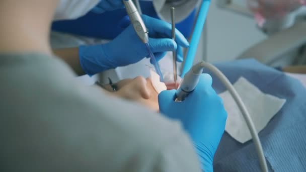 Young woman visiting the dentist. Doctor with dental nurse treating a patient, scaling and polishing the teeth. - Materiał filmowy, wideo