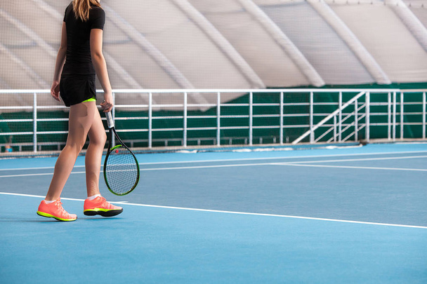 Gambe di giovane ragazza in un campo da tennis chiuso con palla e racchetta
 - Foto, immagini