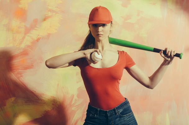 Όμορφο κορίτσι με κόκκινο καπάκι με πράσινο ρόπαλο και μπάλα - Φωτογραφία, εικόνα