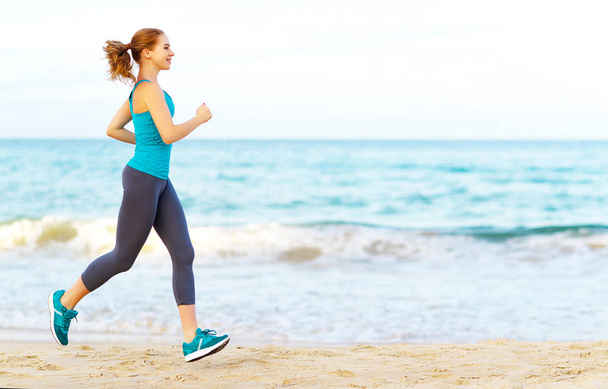 woman goes in for sports jogging on beach - Fotoğraf, Görsel