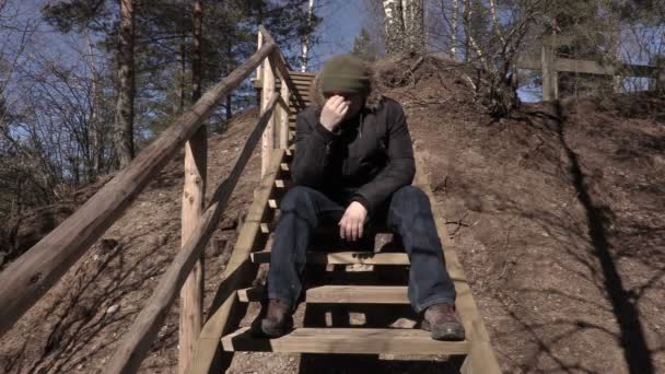 Depressed man sitting on wooden stairs - Footage, Video