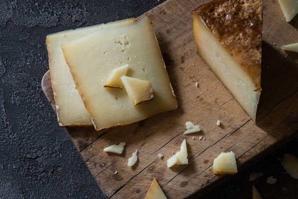 Італійський сир твердий пекоріно Тоскано нарезаєтся а нарізаною на дерев'яну шахівницю - Фото, зображення