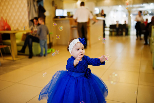 Cute little dziewczynka w niebieskiej sukience grać z baniek mydlanych. 1 wy - Zdjęcie, obraz