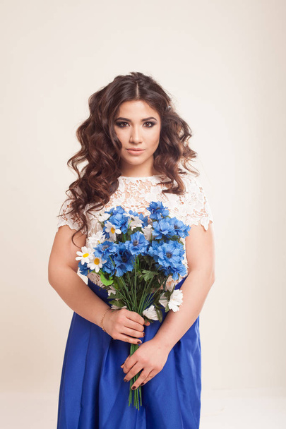 дівчина в сукні з блакитними квітами в руках
 - Фото, зображення