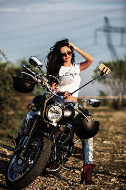 Beautiful motorcycle brunette woman with a classic motorcycle (c - Foto, Imagen