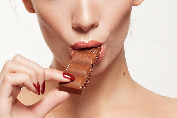 Lovely smiling teenage girl eating chocolate - Zdjęcie, obraz