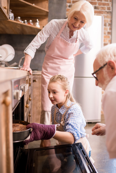girl placing pie in oven - Photo, Image