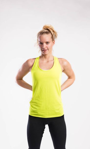 Attractive young fitness woman in yellow tank top. Studio shot. - Fotografie, Obrázek