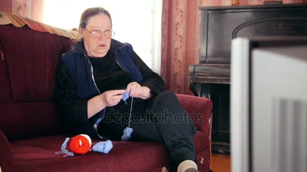 Πορτρέτο του ένα σπίτι βλέποντας τηλεόραση ανώτερος κυρία πλέκει κάλτσες μαλλιού - Πλάνα, βίντεο