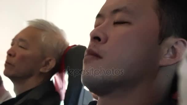 Asian man looks tired and try to sleep during flight on air plane - Záběry, video