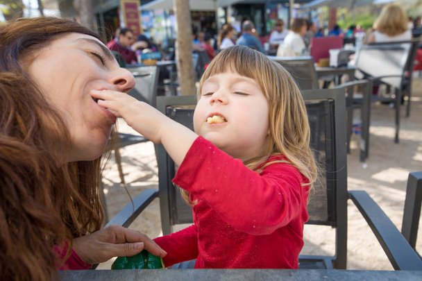 ребенок и мать едят вместе слоеный сыр в кафе на террасе
 - Фото, изображение
