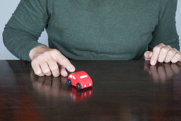 человек пальцем указывает на игрушечный автомобиль
 - Фото, изображение