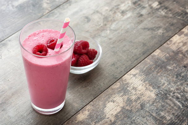 Raspberry smoothie in glass on wooden table - Photo, Image