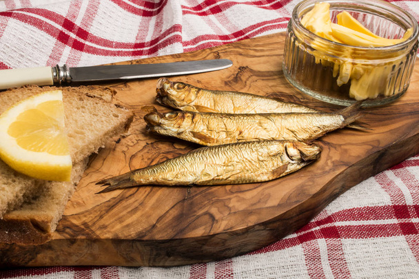 golden brown smoked sprats on wooden board - Photo, Image