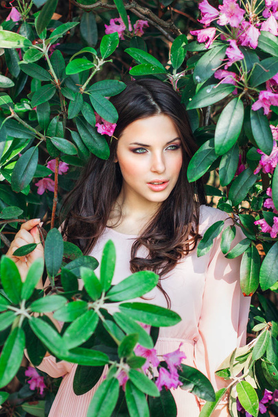 Portrait of young beautiful woman posing among blooming trees - Foto, Imagem