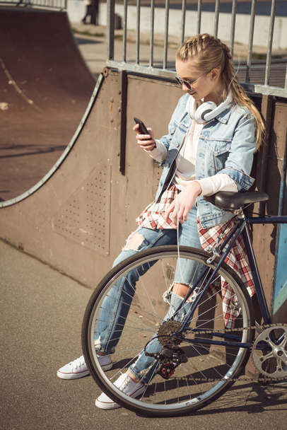 Girl with bike using smartphone  - Valokuva, kuva