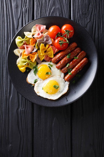copieux petit déjeuner : œufs frits, saucisses, pâtes farfalle et tomate
 - Photo, image
