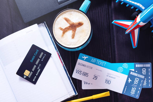 Laptop, vliegtuig tickets, koffie, creditcard ligt op tafel - Foto, afbeelding