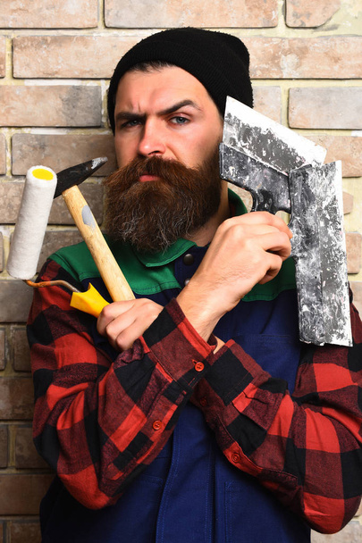 bearded painter man holding various building tools with serious face - Fotoğraf, Görsel