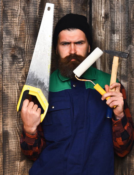 bearded man holding various building tools with serious face - Foto, Bild