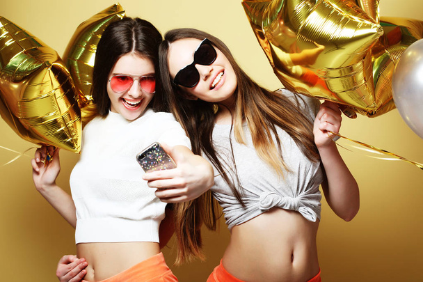 Two teenage girls friends with gold balloons  make selfie on a p - Fotografie, Obrázek