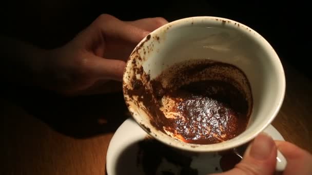 Auf dem Kaffeesatz ratend hält eine weibliche Hand einen Kaffeebecher mit Kaffeesatz. Nahaufnahme. - Filmmaterial, Video