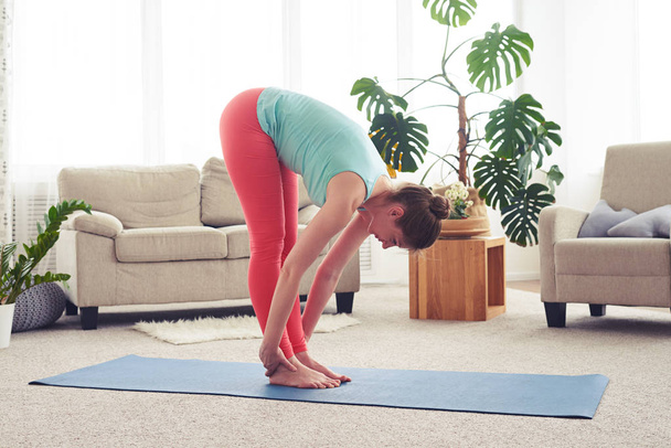 Magro femminile che si estende sul compagno di yoga in soggiorno
 - Foto, immagini