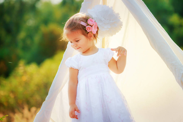 Ένα μικρό κορίτσι στέκεται από λευκό καλύβα στη φύση - Φωτογραφία, εικόνα