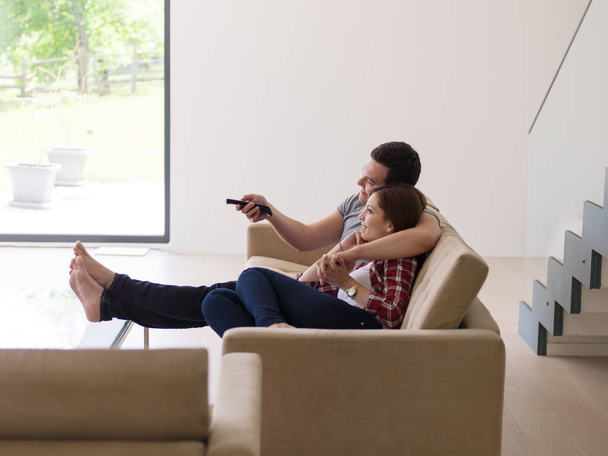 Young couple on the sofa watching television - 写真・画像