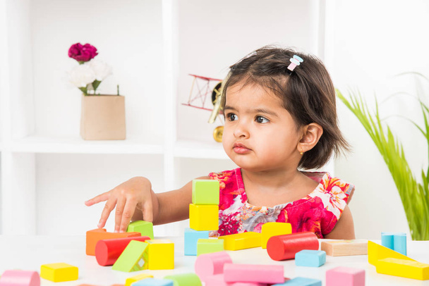indio lindo y feliz bebé niña jugando con juguetes sobre la mesa
 - Foto, Imagen