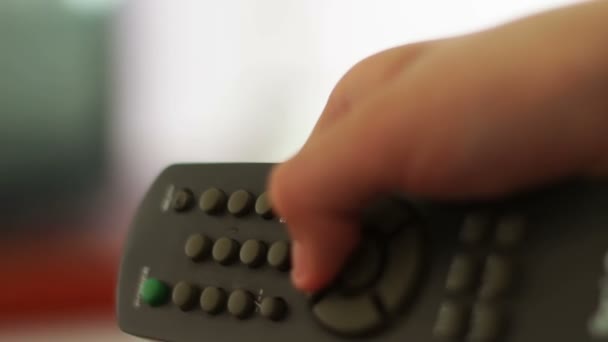 Close-up tiro de uma mão masculina segurando o controle remoto TV e mudando de canais de televisão
 - Filmagem, Vídeo
