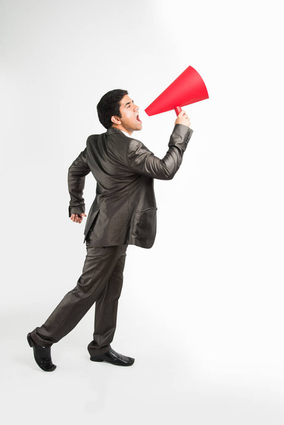 homme d'affaires indien annonçant ou diffusant des nouvelles en utilisant haut-parleur rouge ou méga micro composé de papier, isolé sur fond blanc
 - Photo, image