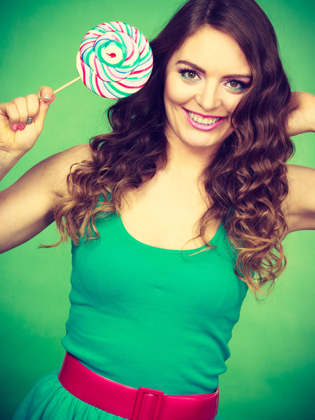 Smiling girl with lollipop candy on green  - Фото, зображення