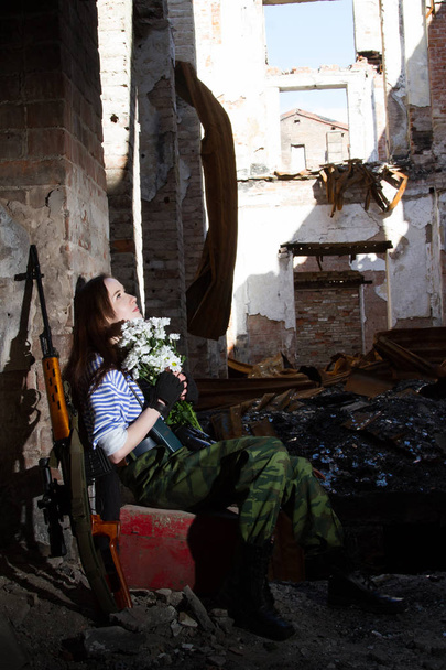 Girl sniper on the ruins with a bouquet of flowers - Photo, Image