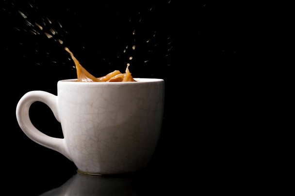 Kopje spatten koffie op zwarte achtergrond - Foto, afbeelding