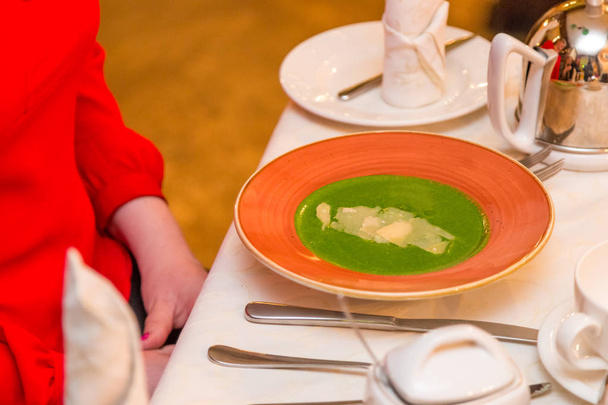 шпинатний суп на червоній тарілці. вона розраховує скористатися посудом. Здорове харчування та корисна їжа
 - Фото, зображення