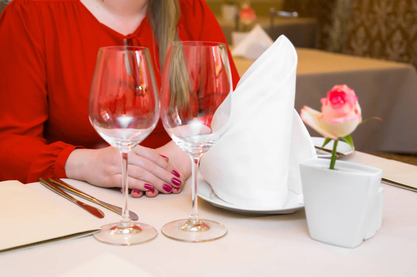 Durk in red is waiting at the restaurant. Table set service with silverware and glass stemware at restaurant before. - Photo, image