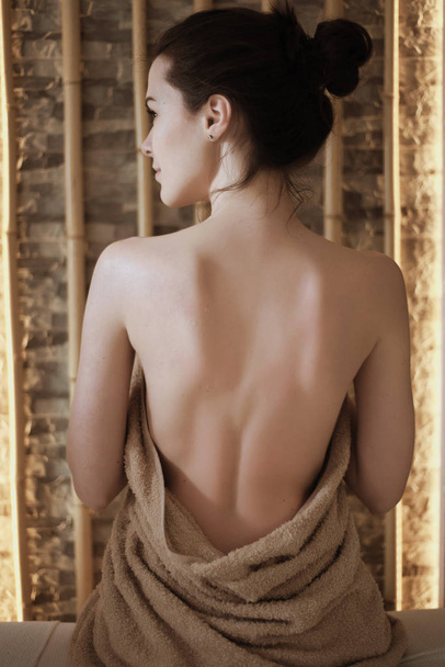 Naked back of a young woman meditating sitting on a bed in front - Foto, Imagen